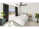 A bright bedroom features a black ceiling fan, a plush bed, and views of the outdoor landscape at 4412 Beckel Rd, Willow Springs, NC 27592