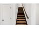 A staircase with light wood treads and dark risers, complemented by white walls and a dark wood handrail at 4412 Beckel Rd, Willow Springs, NC 27592