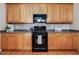 Well-lit kitchen featuring wooden cabinets, modern black appliances, and a tile backsplash at 5910 Lacebark Ln, Durham, NC 27713