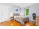 Comfortable bedroom with hardwood floors, a cozy bed, and a view of the outside greenery at 601 Lee St, Durham, NC 27701