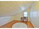 Cozy attic space with wood floors, white paneled walls and ceiling, and a sitting area beneath a window at 7055 Old 421 Rd, Liberty, NC 27298
