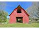 Front view of a well-maintained red barn, showcasing its classic design and sturdy structure on a grassy field at 7055 Old 421 Rd, Liberty, NC 27298