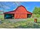 View of the red barn with an open bay door, clear blue sky, and a small yard at 7055 Old 421 Rd, Liberty, NC 27298