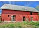Side view of a red barn featuring weathered doors, corrugated metal, and a sturdy structure, showcasing rustic charm at 7055 Old 421 Rd, Liberty, NC 27298