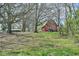Scenic shot of a red barn and surrounding structures framed by majestic trees, showcasing the property's serene ambiance at 7055 Old 421 Rd, Liberty, NC 27298
