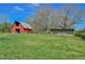 Spacious property featuring a classic red barn and additional structure, surrounded by lush green grass and mature trees at 7055 Old 421 Rd, Liberty, NC 27298