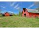 Two red barns on a large, grassy field with a clear blue sky at 7055 Old 421 Rd, Liberty, NC 27298