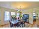 Elegant dining room with a chandelier, table set for six, and large windows with sheer curtains at 7055 Old 421 Rd, Liberty, NC 27298