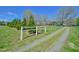 Gravel driveway leads to a charming home, framed by lush greenery and a white picket fence at 7055 Old 421 Rd, Liberty, NC 27298