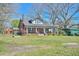 Quaint brick farmhouse with covered porch, mature trees, and outbuildings at 7055 Old 421 Rd, Liberty, NC 27298