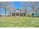 Charming brick home with a welcoming front porch and lush green lawn under a clear blue sky at 7055 Old 421 Rd, Liberty, NC 27298