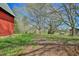 Expansive view of a property featuring a classic red barn and outbuildings amidst mature trees and green pasture at 7055 Old 421 Rd, Liberty, NC 27298