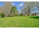 Lush green field showcasing the spaciousness and natural beauty of the property, dotted with mature trees and structures at 7055 Old 421 Rd, Liberty, NC 27298