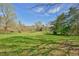 Picturesque landscape view of a grassy field surrounded by mature trees and foliage, highlighting the property's tranquility at 7055 Old 421 Rd, Liberty, NC 27298