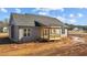 View of the home's rear exterior featuring a wooden patio, gray siding, and an unfinished yard at 9315 Turkey Way, Middlesex, NC 27557