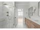 Bright bathroom featuring a marble tile shower, double vanity with light wood cabinets, and view into the bedroom at 100 Sire Ct, Holly Springs, NC 27540