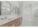 Bright bathroom featuring a marble tile shower, double vanity with light wood cabinets, and elegant fixtures at 100 Sire Ct, Holly Springs, NC 27540