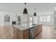 Open kitchen with a large island, stainless steel dishwasher, and modern pendant lights at 100 Sire Ct, Holly Springs, NC 27540