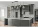 Stylish kitchen features dark gray cabinets, stainless fridge, marble backsplash, island with quartz counter and pendant lights at 100 Sire Ct, Holly Springs, NC 27540