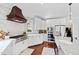 Bright kitchen featuring stainless appliances, custom range hood, white cabinetry, and hardwood floors at 1004 Colworth Way, Raleigh, NC 27614
