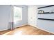 Bright bedroom featuring light blue walls, wood floors, closet, window and floating shelves at 120 Galax Ln, Durham, NC 27703