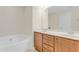 Bathroom featuring double sinks, wooden cabinets, a soaking tub, and large mirror at 146 Skyros Loop, Cary, NC 27519