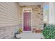 Inviting front entryway with a colorful door, stone accents, and decorative potted plants at 146 Skyros Loop, Cary, NC 27519