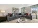 Spacious living room with an L-shaped gray sofa, accent pillows, modern coffee tables and large window at 186 Ethel Ln, Angier, NC 27501