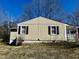 A charming home featuring vinyl siding and complementing brown shutters against a blue sky backdrop at 2001 S Ashland Dr, Burlington, NC 27217