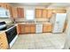 Bright kitchen features oak cabinets, stainless sink and white appliances, tile floors at 2001 S Ashland Dr, Burlington, NC 27217