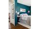 Bedroom featuring hardwood floors, teal walls, a round mirror, and bright natural light at 204 E Murray Ave, Durham, NC 27704