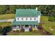 Aerial front view of home with a green metal roof, inviting porch, and manicured landscaping at 220 Epps Clark Rd, Siler City, NC 27344