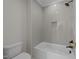 Modern bathroom with gray tiled walls, bathtub, showerhead, and a toilet with chrome fittings at 2623 Marchmont St, Raleigh, NC 27608