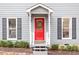 View of the home's red front door with a decorative wreath and gray siding with black shutters at 3212 Oxford Dr, Durham, NC 27707