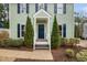Inviting front entrance featuring a blue door, white trim, and neatly trimmed evergreens on the front porch at 3304 Glen Currin Dr, Raleigh, NC 27612