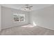 Neutral bedroom featuring carpeted floors, a ceiling fan, and a large window at 4940 Heathshire Dr, Raleigh, NC 27616