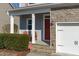 Cozy front porch with stone steps, leading to a vibrant red front door and two chairs at 4940 Heathshire Dr, Raleigh, NC 27616