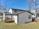 Angled view of the home's rear, highlighting the painted brick, vinyl siding, and wooden deck with stairs at 5704 Whippoorwill St, Durham, NC 27704