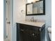 Dark vanity in blue-walled bathroom, featuring granite countertops, a framed mirror and chrome fixtures at 5917 Sentinel Dr, Raleigh, NC 27609