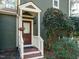Close-up of front door framed by white rails and green siding of this charming home at 5917 Sentinel Dr, Raleigh, NC 27609