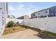 Fenced backyard with a concrete pad, bordered by a row of colorful townhomes at 624 Metro Station, Apex, NC 27502