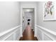 Hallway featuring white wainscoting, hardwood floors, and access to the living areas at 624 Metro Station, Apex, NC 27502