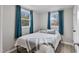 Bright bedroom features modern flooring, two windows with stylish curtains, and cozy bedding at 700 Ross Rd, Lillington, NC 27546
