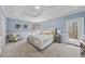 Light filled main bedroom features light blue walls, tray ceiling, and access to deck at 8720 Deerland Grove Dr, Raleigh, NC 27615