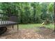 Backyard featuring a deck, playset, and mature trees, creating a private outdoor space at 9249 Miranda Dr, Raleigh, NC 27617