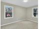 Bedroom with neutral-colored carpet, fresh paint, two windows, and a view of the yard at 1041 Limerick Ln, Durham, NC 27713