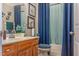 Well-lit bathroom with blue accents, wooden cabinets, and framed artwork adds comfort at 11843 Canemount St, Raleigh, NC 27614