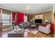 Inviting living room featuring a ceiling fan, fireplace, and large windows with bright red curtains at 11843 Canemount St, Raleigh, NC 27614