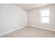 Simple bedroom with neutral carpet, window, and a white door, providing a blank canvas at 122 Weavers Grove Dr, Chapel Hill, NC 27514