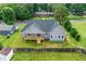 Aerial view of a gray home with a wooden deck surrounded by a green lawn and tall trees at 1604 Palmer Dr, Graham, NC 27253